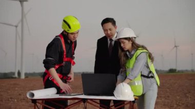 Müfettiş ve bakım mühendisi bir sekreterle birlikte rüzgar türbini alanında elektrik üreten bir projeyi inceliyorlar. Temiz enerji kavramı, yenilenebilir enerji, dünyayı kurtarmak..