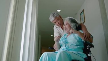 Psikiyatrik semptomları olan yaşlı bir kadın tekerlekli sandalyede ve yaşlı bir çift ona psikiyatri hastanesinde bakıyor. Sağlık sorunları kavramı