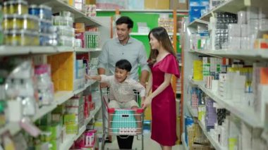 Baba ve oğuldan oluşan çok ırklı bir aile süpermarkette alışveriş arabaları kullanıyor, iyi bir aile ilişkileri olduğu için mutlular..