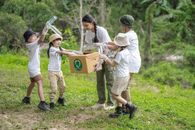 Gönüllü Asyalı ve çocuklar küresel ısınma ve çevre kirliliğini azaltmak için plastik şişeleri çöp kutusuna koyuyorlar. Gönüllü olma ve geri dönüşüm kavramı.