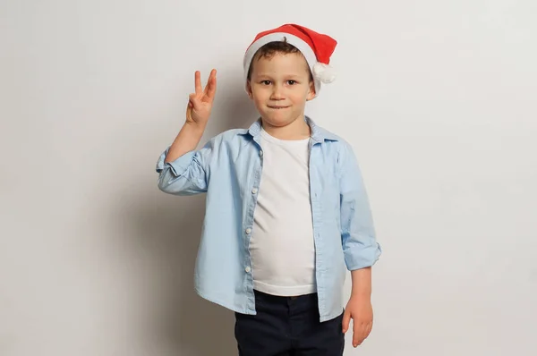 Мальчик Шляпе Санта Клауса Показывает Три Пальца — стоковое фото