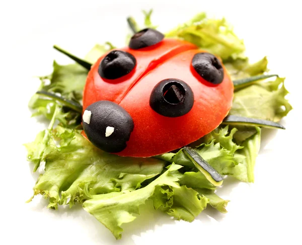 Lieveheersbeestje gemaakt van rauwe tomaat op sla blad — Stockfoto