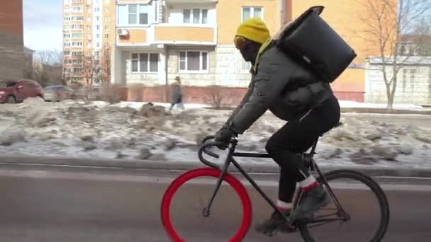 Kolový kurýr s chladící taškou doručující objednávku na červeném kole. Boční pohled — Stock video