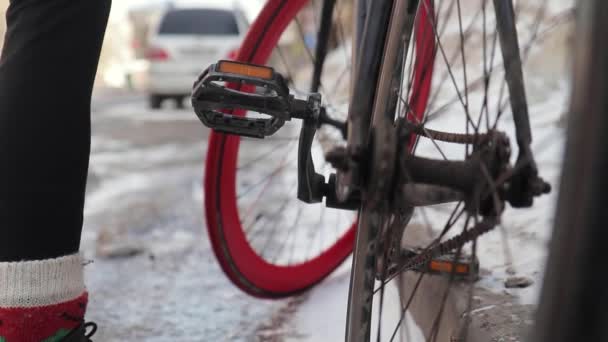Die Beine des Radfahrers treten in die Pedale und setzen das Rad in Bewegung. Sonniger Wintertag — Stockvideo