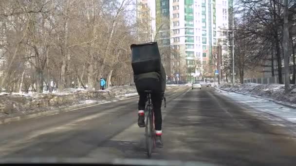 Kurýr s chladnější taškou za zády jezdí v zimě na kole po silnici — Stock video