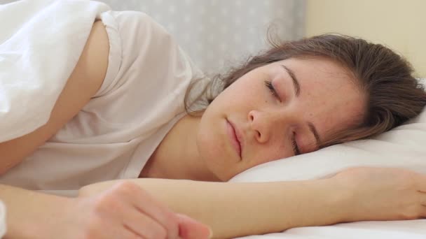 Durmiente chica oye la alarma y cubre su cara con una manta — Vídeos de Stock