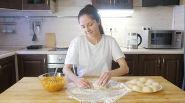 Genç kız ahşap masada elmalı turta yapıyor. Yanında un ve elmalı turta var.