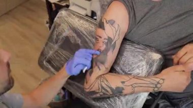 Tattoo artist make tattoo on the mans shoulder with a tattoo machine. Timelapse