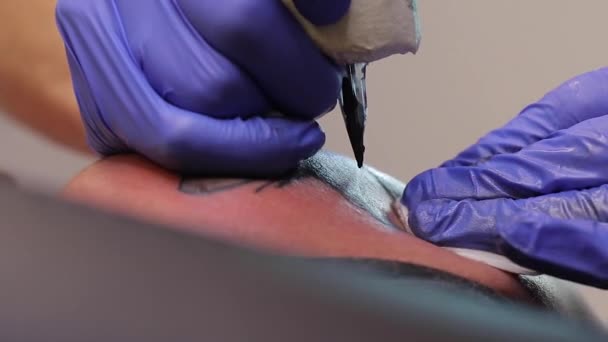 Tatueringskonstnär gör en svart tatuering på mans hud med en tatueringsmaskin. Närbild — Stockvideo