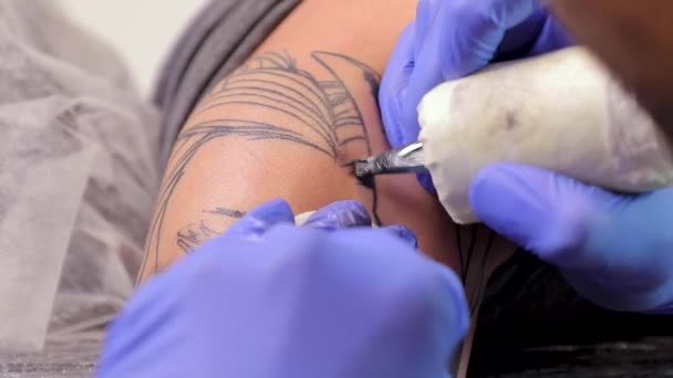 O artista de tatuagem faz uma tatuagem na pele do homem com uma máquina de tatuagem. Fechar — Vídeo de Stock