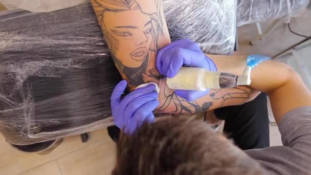 Tattoo umělec dělá tetování na mužském rameni s tetovacím strojem — Stock video