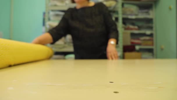 Textile factory worker unrolls a huge roll of fabric on a table — Wideo stockowe