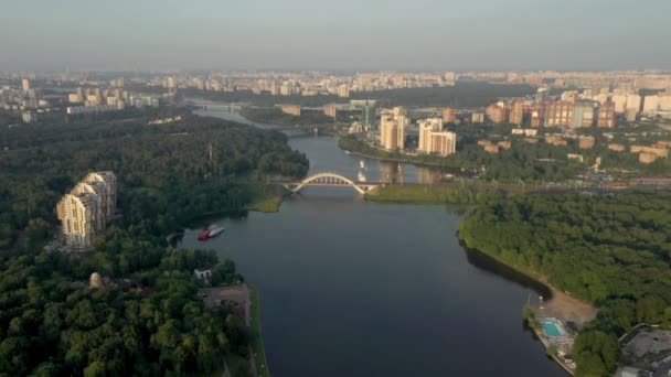 Drone shooting a green area with high-rise buildings, river and bridge in summer — Vídeo de Stock