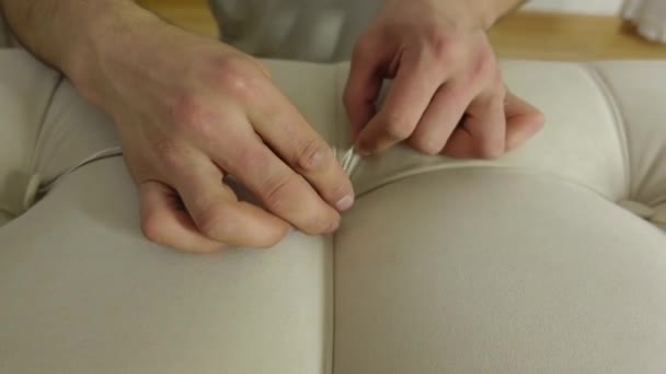 Man upholster bed with new fabric and insert buttons with sewing needle — Vídeo de Stock