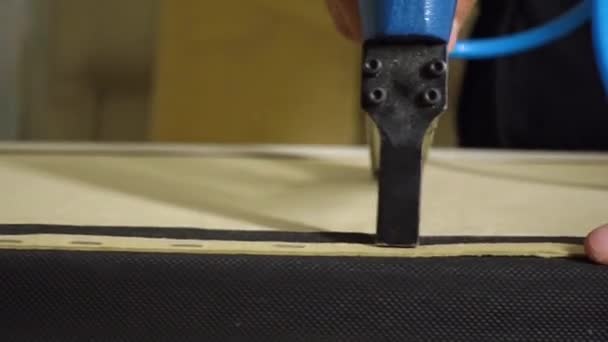 Mãos de homem estofado parte da cama com novo tecido usando um grampeador de móveis — Vídeo de Stock