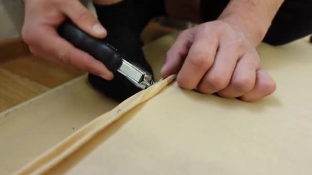 Man handen verwijderen oude bekleding uit een deel van het bed met nietjesverwijderaar — Stockvideo