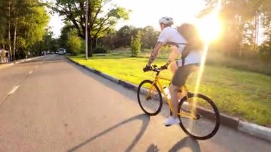 Bisikletçiler yaz aylarında yeşil caddelerin arasında asfalt yolda bisiklet sürerler. Arka plan