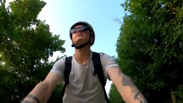 Cycliste promenades sur un chemin dans un parc en été parmi les arbres. Vue du bas — Video