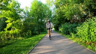 Bisikletçi yazın ağaçların arasında bir parkta bir patikaya biner. Ön görünüm