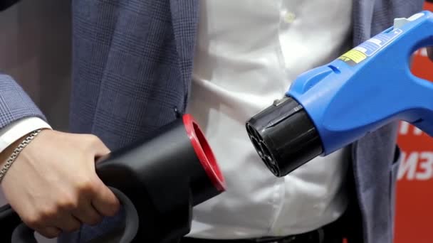 Человек в пиджаке вставляет шнур электрического автомобиля зарядной станции в розетку — стоковое видео