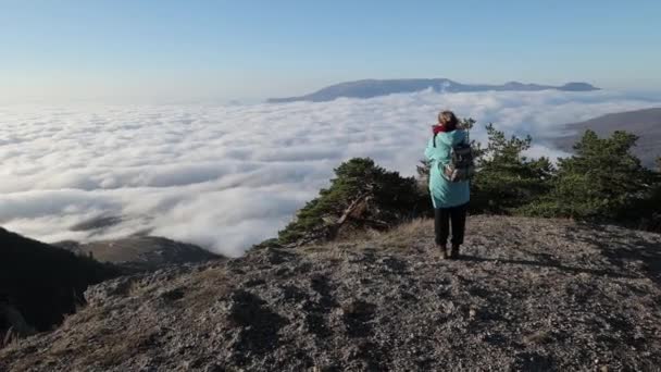 Fotograf står på toppen av berget högt över molnen och tar ett foto — Stockvideo