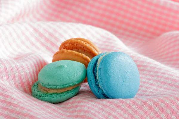 Groupe de macarons colorés sur tissu rose . — Photo