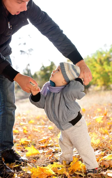 Niño dando los primeros pasos con la ayuda del padre — Foto de Stock