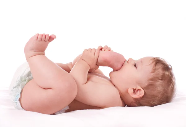 Closeup portret van babyjongen zijn voeten nemen in zijn mond — Stockfoto