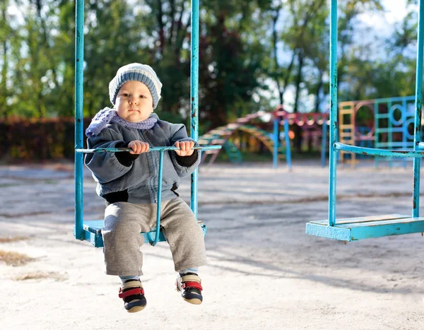 Baby boy playing on swing in autumn park — Stock Photo, Image