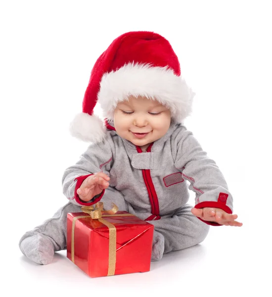 Младенец в шляпе Санта-Клауса играет с рождественской подарочной коробкой — стоковое фото