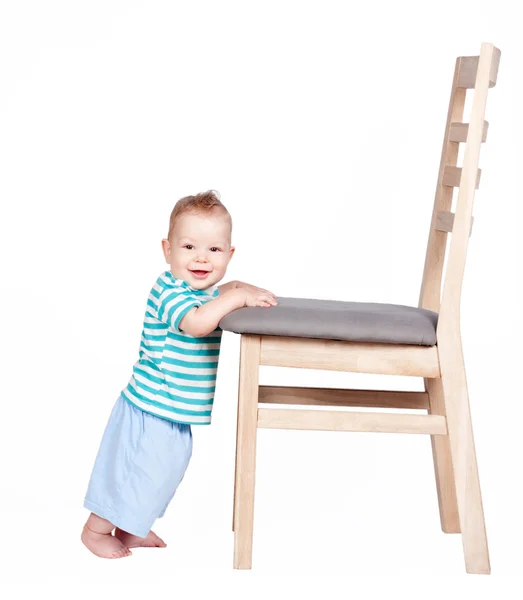 Bébé garçon debout contre une chaise isolée sur blanc — Photo