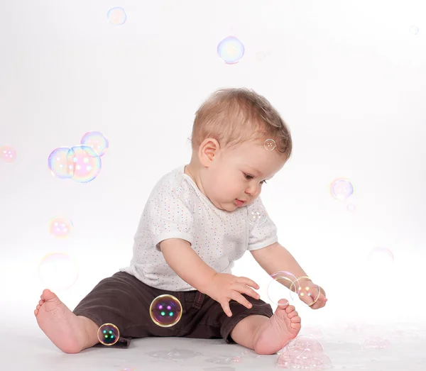 Хлопчик грає з мильними бульбашками на білому Стокова Картинка