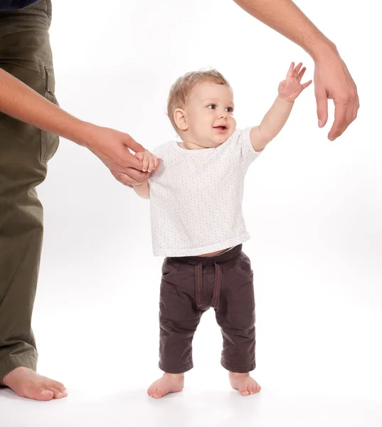 Ребенок делает первые шаги с отцом помощь на белом Лицензионные Стоковые Фото