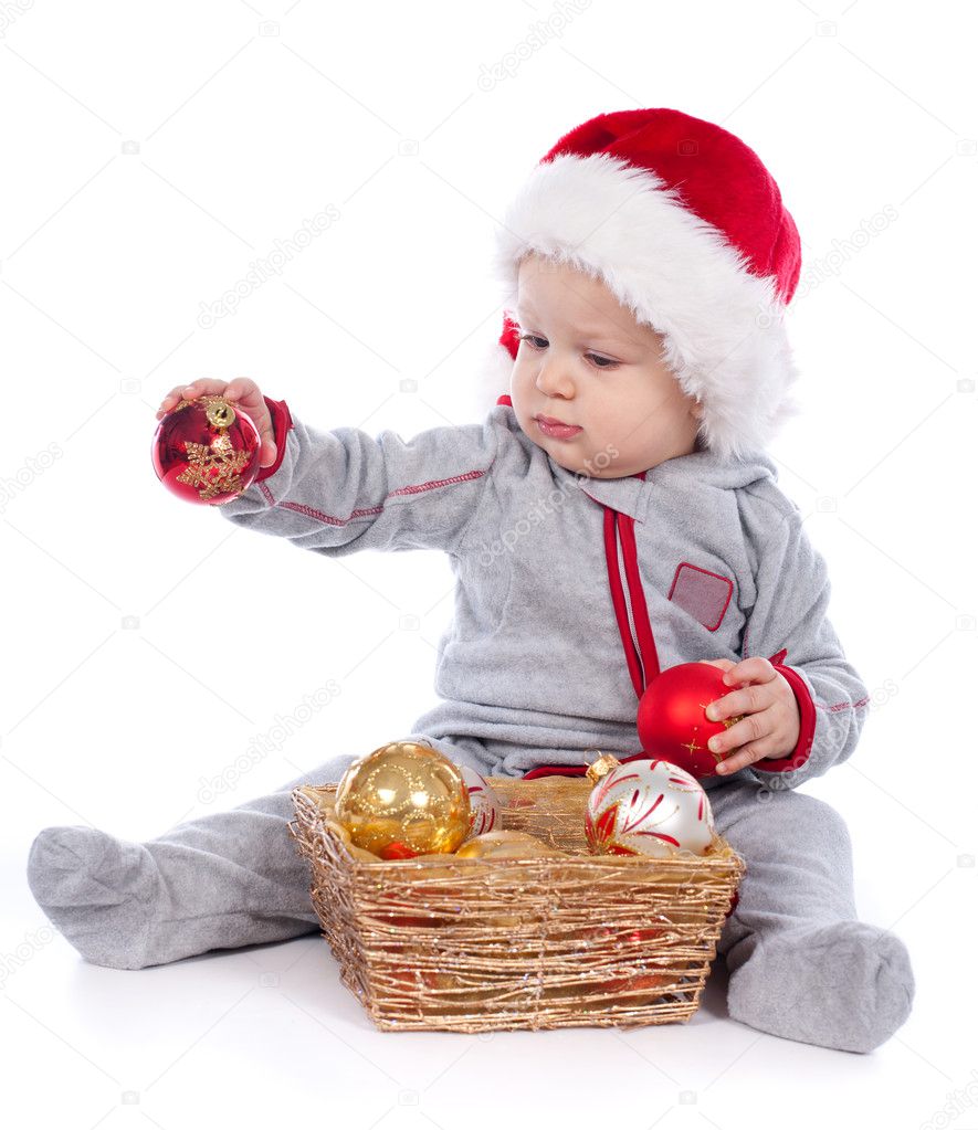 Baby in Santa hat playing with Christmas balls isolated on white