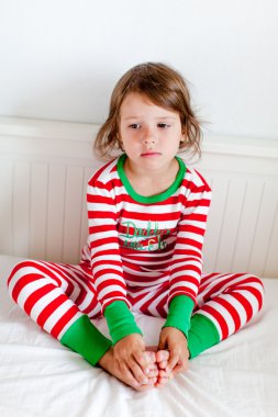 küçük kız yatağında oturup Çizgili Pijama içinde
