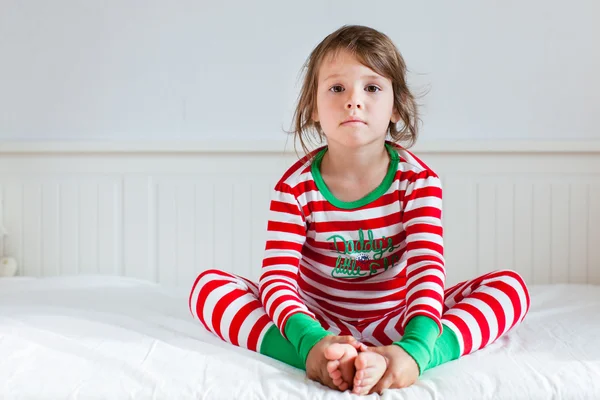 küçük kız yatağında oturup Çizgili Pijama içinde