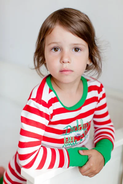 Portrait of small girl in pajamas sitting on the bed — Stock Photo, Image