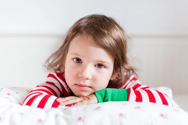 Petite fille en pyjama rayé couchée sur son lit — Photo