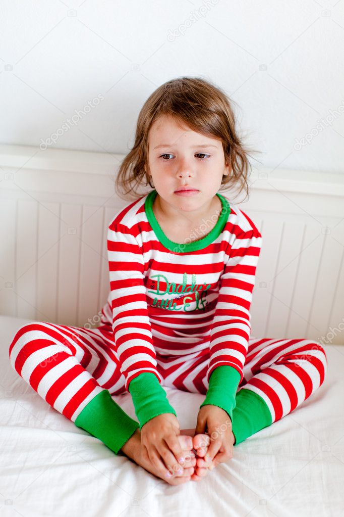 Small girl in striped pajamas sitting on her bed — Stock Photo © azaza