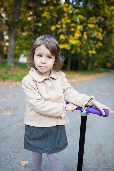 Preschooler girl outdoor in the park with scooter — Stock Photo, Image