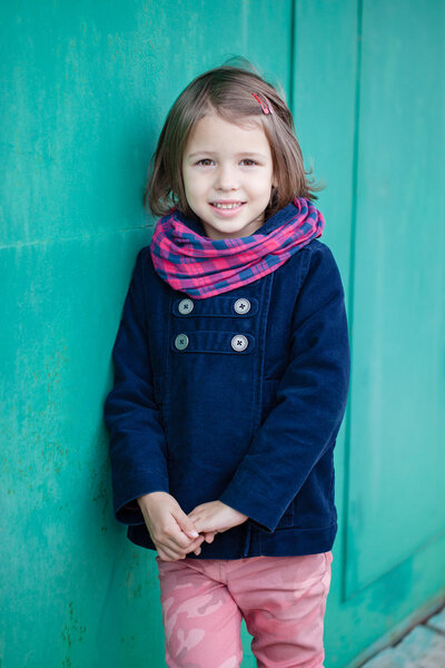 Portrait of preschooler girl near green wall