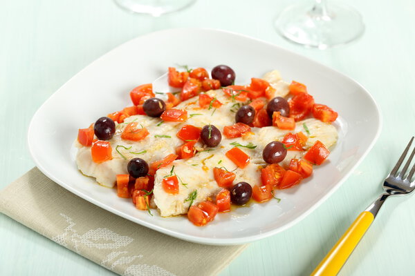cod fillets with tomatoes and olives on white plate