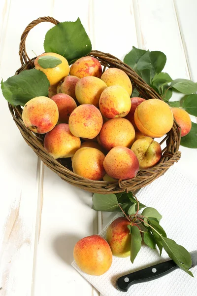 Apricot in rieten mand met houten tafel — Stockfoto