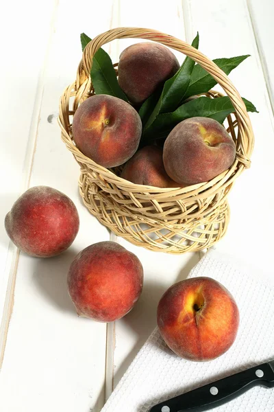 Персики в плетеному кошику дерев'яний стіл — стокове фото