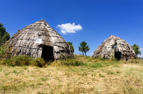 Two traditional straw huts in greek country, on a sunny day