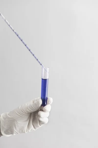 Tenuta a mano di una provetta con liquido blu — Foto Stock
