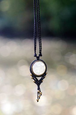 Beyaz ay taşlı doğal arka planda Boho kolyesi