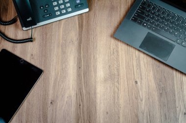 Bir dizüstü bilgisayar ve telefon gösteren bir ofis masasının en alt görüntüsü