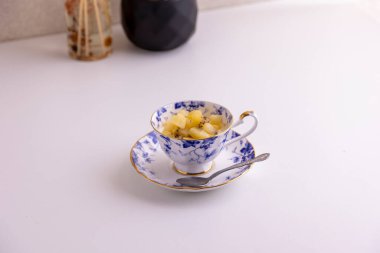 Lezzetli peynirli kek ve çay fincanında yapılmış kivi meyvesi.