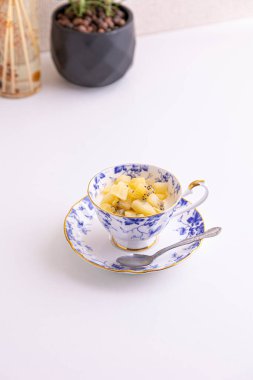 Lezzetli peynirli kek ve çay fincanında yapılmış kivi meyvesi.